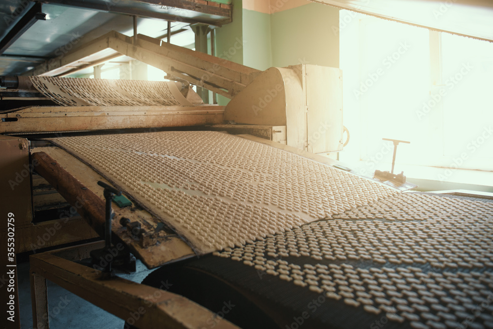 Obraz premium Bakery production line with sweet cookies on conveyor belt, confectionery factory workshop.