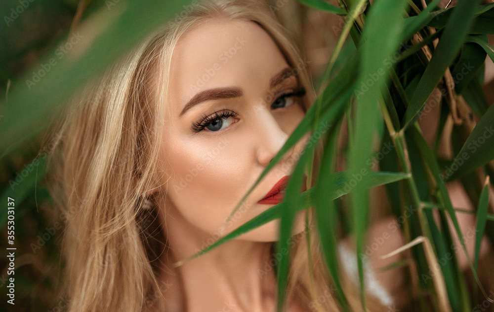 Beautiful young blonde woman among the grass, and strictly looks at the camera, closeup portrait, big eyes Beautiful young blonde woman among the grass, and strictly looks at the camera, closeup portrait, big eyes