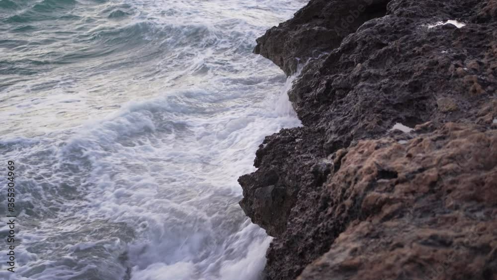 Angry sea breaking furiously against the waves. The water splashes hard. Sunset Angry sea breaking furiously against the waves. The water splashes hard. Sunset