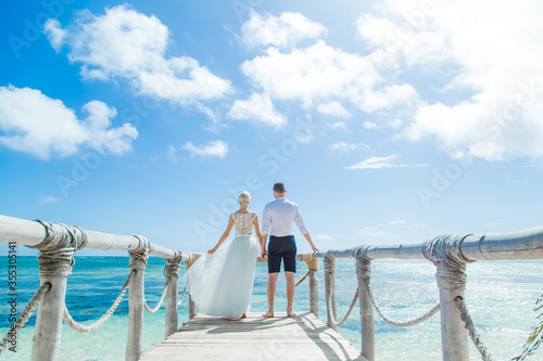 Bild auf Leinwand Newlyweds holding hands hugging at white sandy tropical caribbean beach landscap