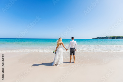 Foto Newlyweds holding hands hugging at white sandy tropical caribbean beach landscap