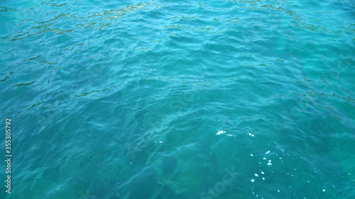 Blue glossy surface of the ocean with ripples and reflection of sunlight, selected sharpness