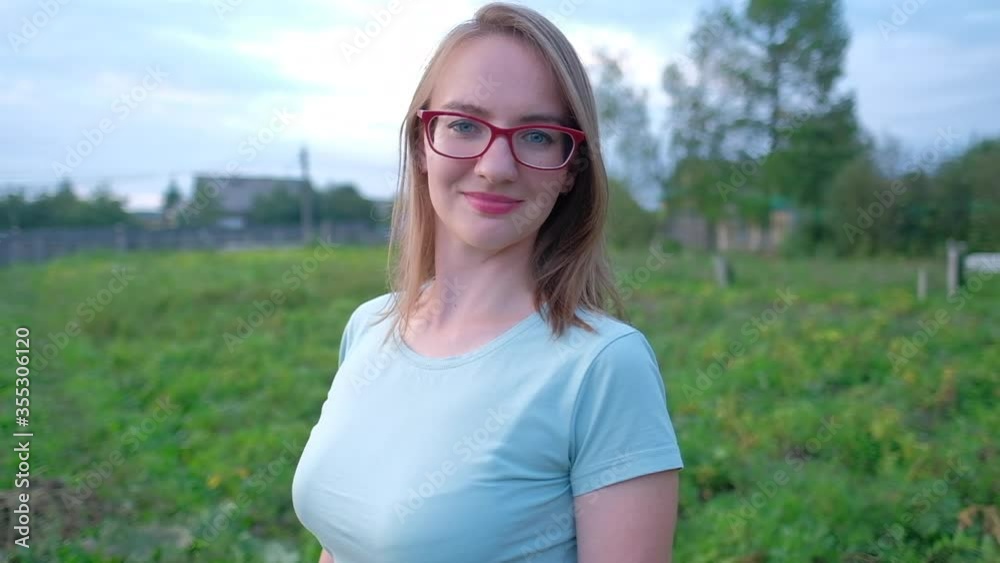 Caucasian woman in glasses looks at the camera and smiles with rural background Caucasian woman in glasses looks at the camera and smiles with rural background