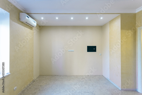 small unfurnished room with yellow walls, wall safe and air conditioning