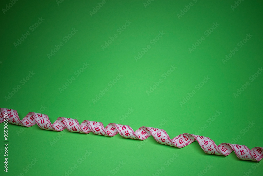 Red measuring tape on green background. Loss weight concept. Top view. Copy space. Isolated. . High quality photo