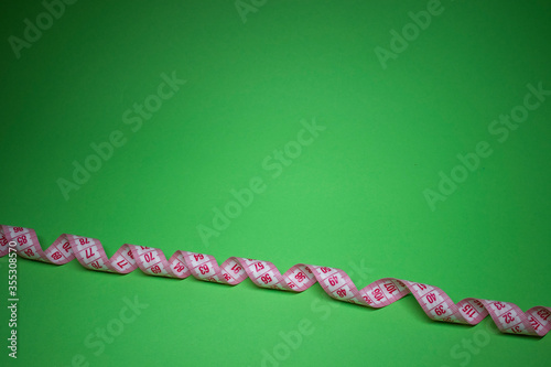 Red measuring tape on green background. Loss weight concept. Top view. Copy space. Isolated. . High quality photo