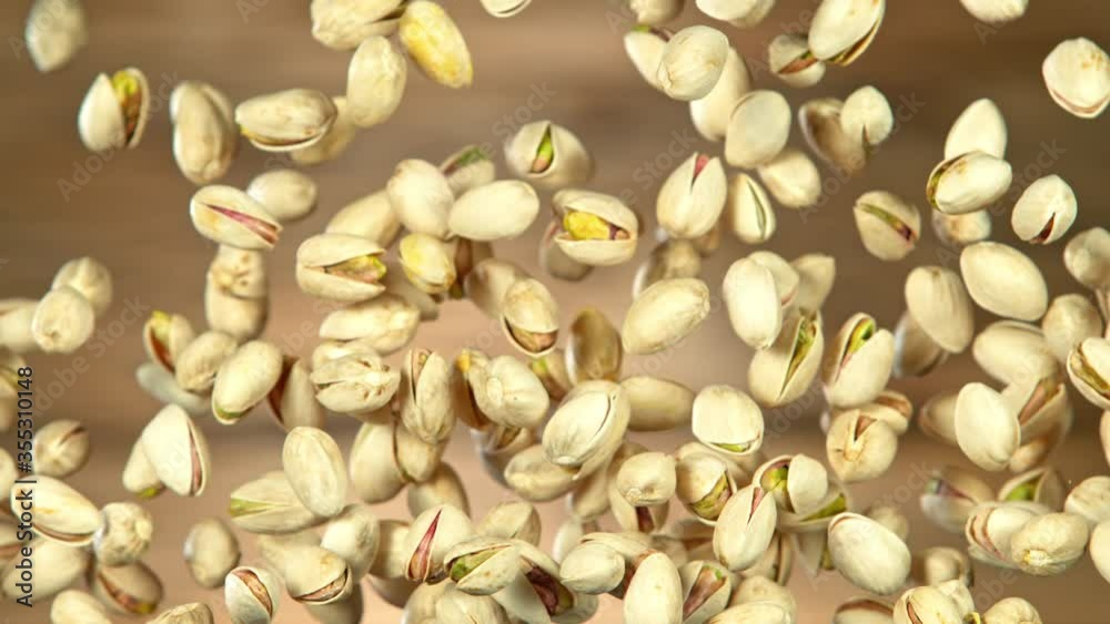 Super Slow Motion Shot of Flying Pistachios After Being Exploded on Wooden Background at 1000fps. Super Slow Motion Shot of Flying Pistachios After Being Exploded on Wooden Background at 1000fps.