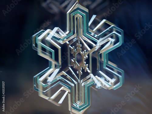 Rotating around its own axis multi-layer metal snowflake; toned in turquoise; close-up. photo