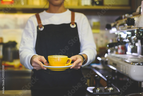 Coffee Business Concept.Asian woman wear blue apron holding hot coffee cup Submit to the customer