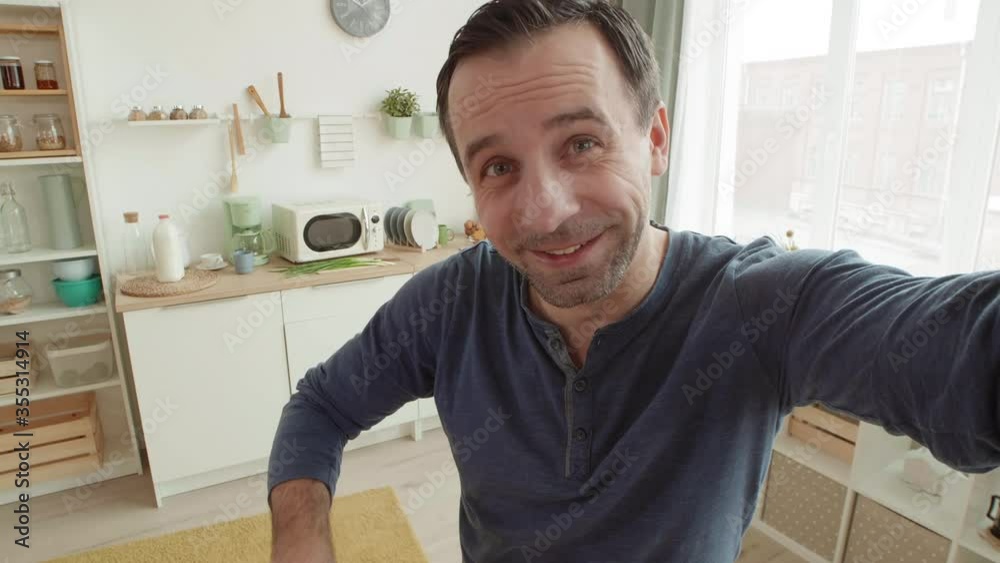 Close up of cheerful Caucasian man standing at kitchen table, unpacking delivered parcel from restaurant while having video conversation with friend Close up of cheerful Caucasian man standing at kitchen table, unpacking delivered parcel from restaurant while having video conversation with friend
