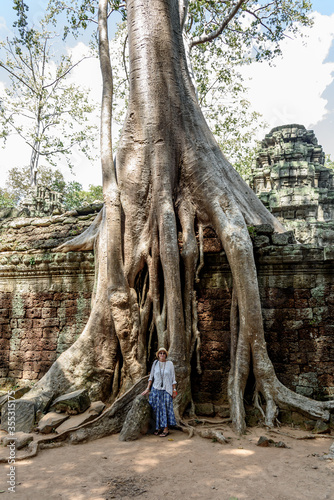 Caucasian Woman Posing Next to a Huge Ficus Tree Roots Covering Walls at Ta Prohm Temple at Angkor Wat Siem Reap Cambodia