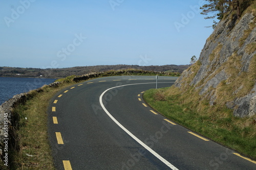 Regional road with sweeping right bend located between rock face and lake, Dromahair, County Leitrim, Ireland