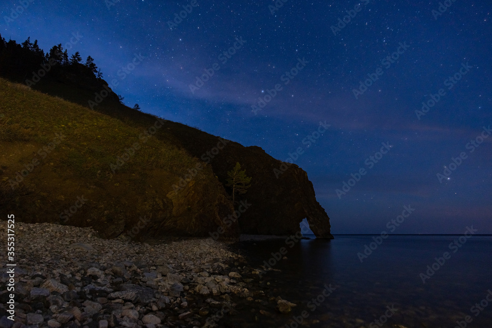 Night landscape with a view of the stone arch on the shore of Lake Baikal