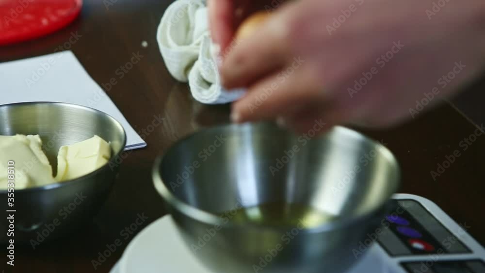 closeup female hands breaking up raw eggs into metal bowl standing on scales closeup female hands breaking up raw eggs into metal bowl standing on scales