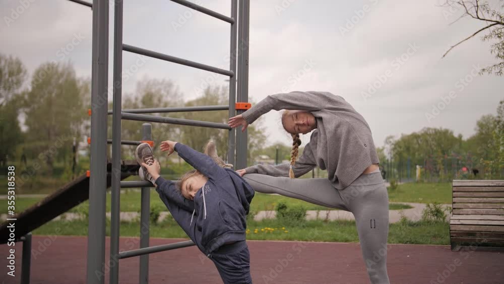 4K Mother and daughter doing exercises on open air sport playground