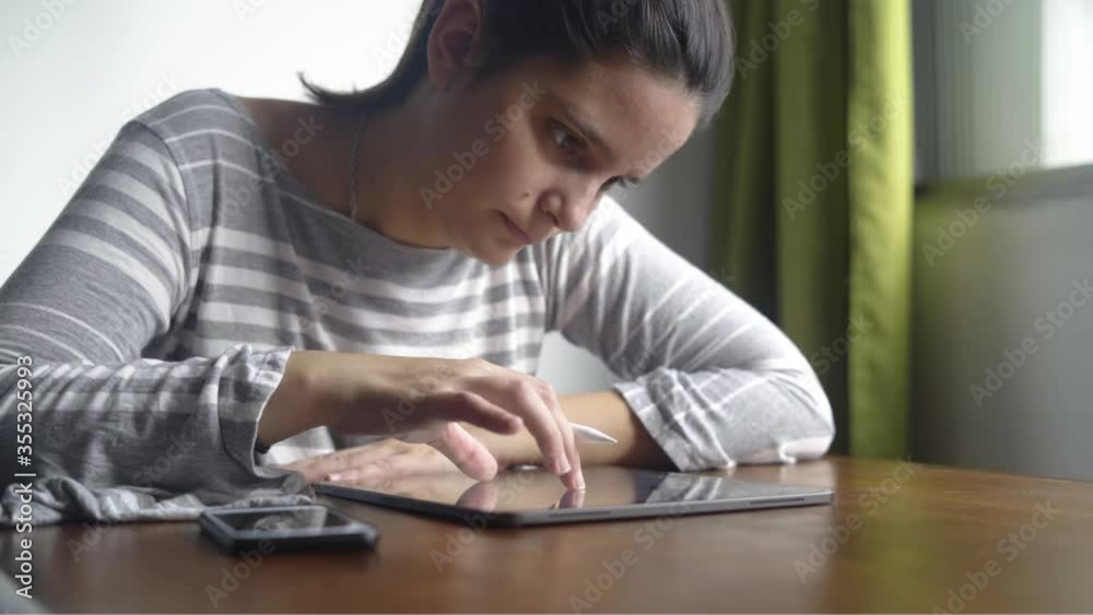 Brunette woman using tablet sitting near the window Brunette woman using tablet sitting near the window