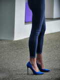 Woman wearing tight jeans and blue high heels shoes close up view.