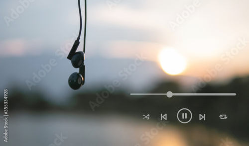 Valokuva Headphones and playlist listen to music at sunset