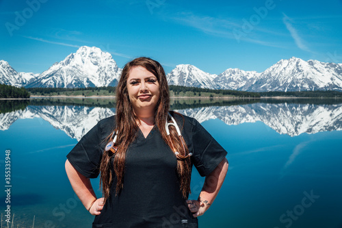 Woman nurse in black scrubs with a stethoscope in the mountains