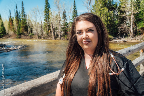 Woman nurse in black scrubs with a stethoscope in the mountains