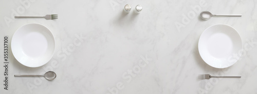 Photos Marble dinning table with two set of white plate and silverware, seasoning bottl