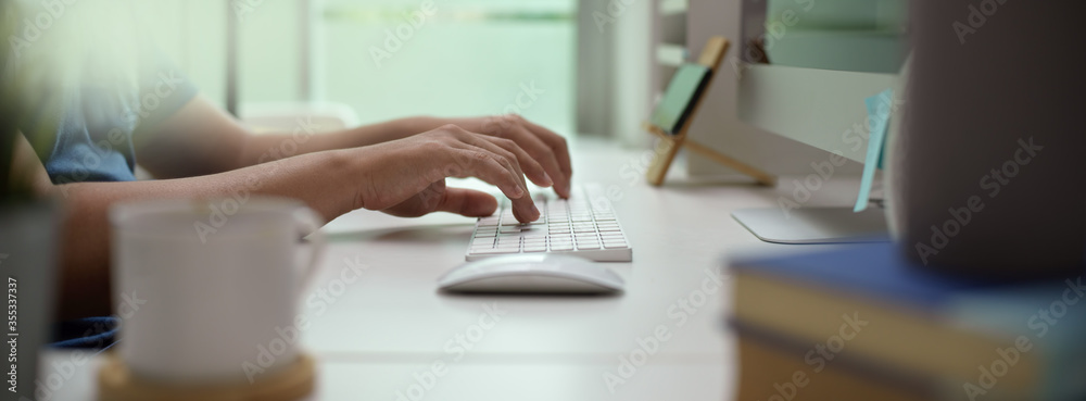 Male entrepreneur typing on computer device on white office desk in modern office room - obrazy, fototapety, plakaty 