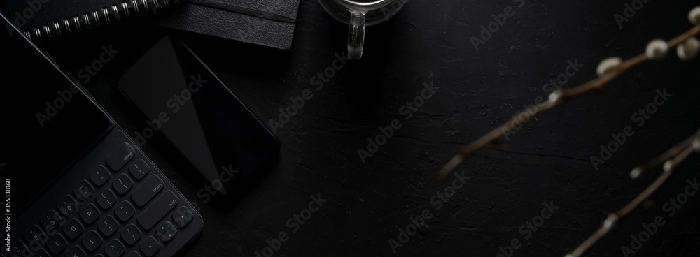 Dark modern concept workspace with digital devices, stationery, coffee cup and copy space
