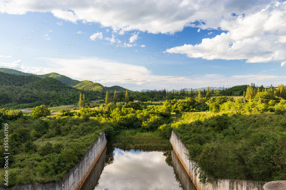 Lake dam water reservoir with mountain forest in beautiful clouds and beautiful blue sky, reservoir for innovations in agro-industry, irrigation.