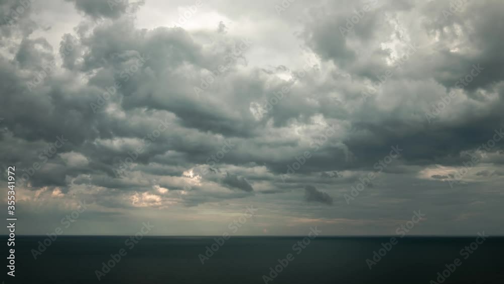 Aerial cloudscape cloudy sky timelapse over the water of Lake Michigan as a storm blows through at dusk just before the sun sets creating orange colored clouds on a blue sky. Aerial cloudscape cloudy sky timelapse over the water of Lake Michigan as a storm blows through at dusk just before the sun sets creating orange colored clouds on a blue sky.