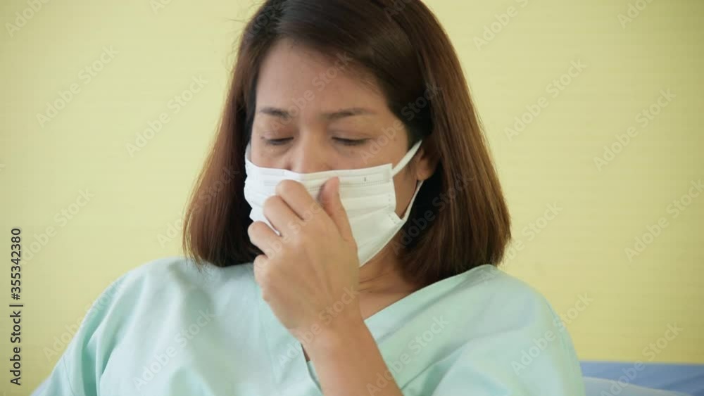 Asian woman patient wearing mask illness from respiratory disease admit to hospital get cough and have a fever Asian woman patient wearing mask illness from respiratory disease admit to hospital get cough and have a fever