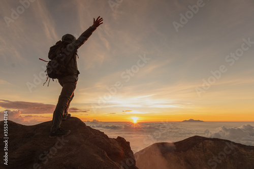 the man backpacker on top of the vulcano agung meets the sunrise. crater view. Higher than clouds. rinjani view. High quality. Bali - island of gods. Indonesian mountains. trekking rote to summit.  photo