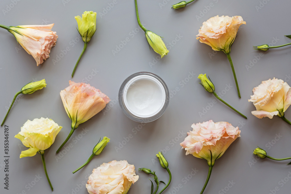 Facial cream on gray background with flowers. Flat lay, top view, mockup, template. High quality photo - obrazy, fototapety, plakaty 