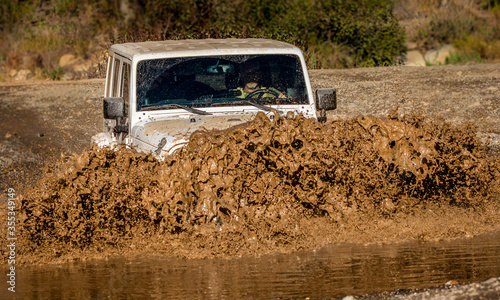 Obraz na plátně A  4x4 vehicle crossing stream creating wave of mud in Trabucco Canyon Californi