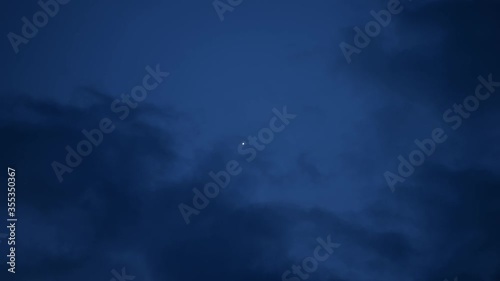 Clouds float against the background of a lone star in the twilight close-up, and then it disappears behind the clouds