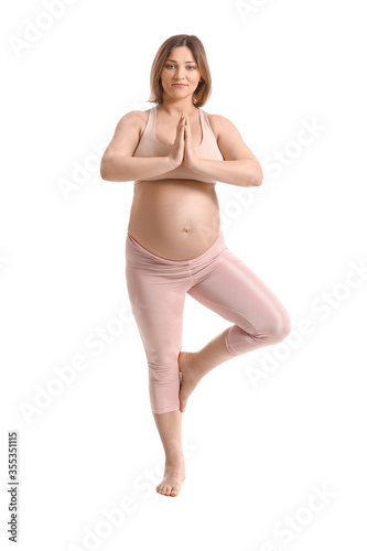Young pregnant woman practicing yoga on white background