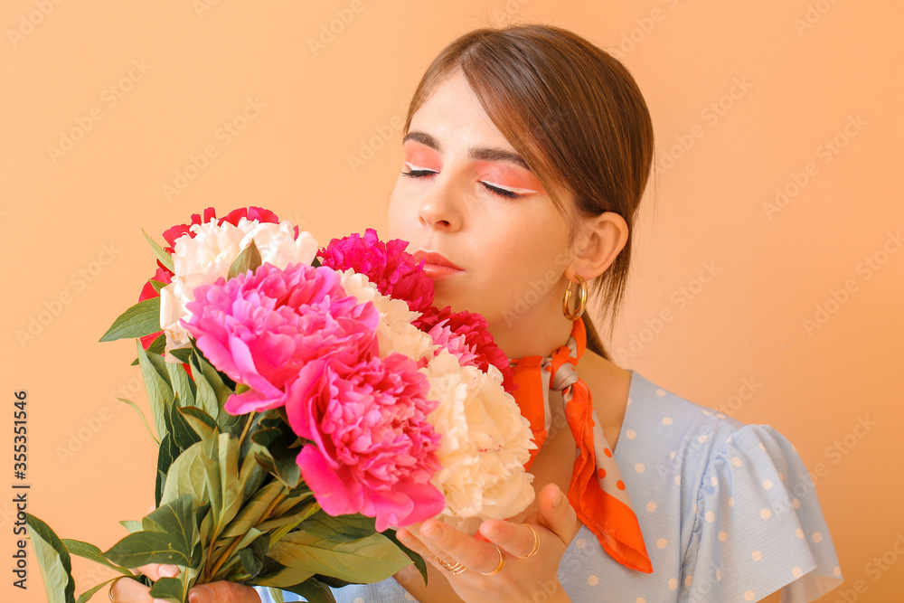 Young woman with beautiful peony flowers on color background