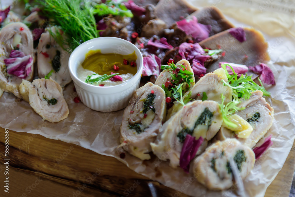 Φωτογραφία Cold appetizers of chicken and other meats, served on a wooden plate with mustard and horseradish sauce, close-up
