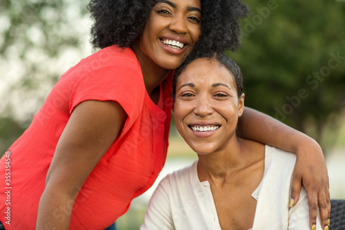 African American mother hugging her adult daughter.