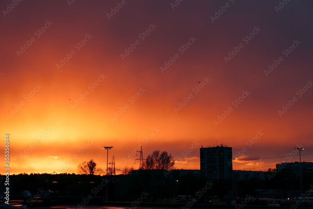 Golden fire sunset with clouds in Riga with silhouette of the buildings trees Golden fire sunset with clouds in Riga with silhouette of the buildings trees
