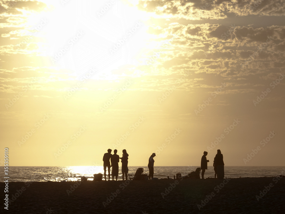 Fototapeta premium Silhouette of people enjoying beach at sunset with dog