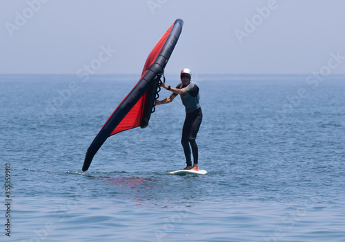 Wing foil in the Pacific Ocean Japan. A man is using an Inflatable wing with a board in the ocean, it is a new sport. Its is red and the ocean blue. photo