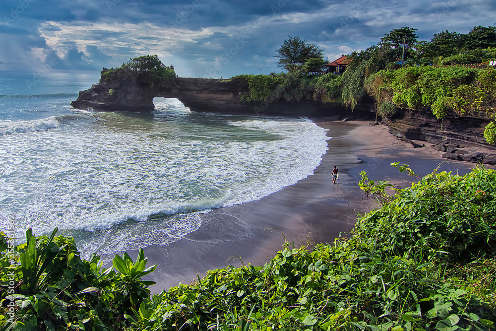 Great landscape shot of a beach in Tanah Lot Bali where a surfer getting ready to surf