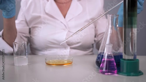 A female scientist in a lab mixes liquids in a Petri dish and gets a visual reaction. Laboratory analysis using reagents. The concept of science, chemistry.