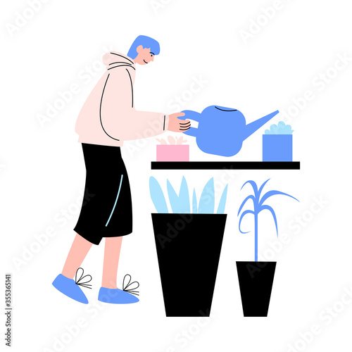 Young man watering and taking care of plants at home during weekday