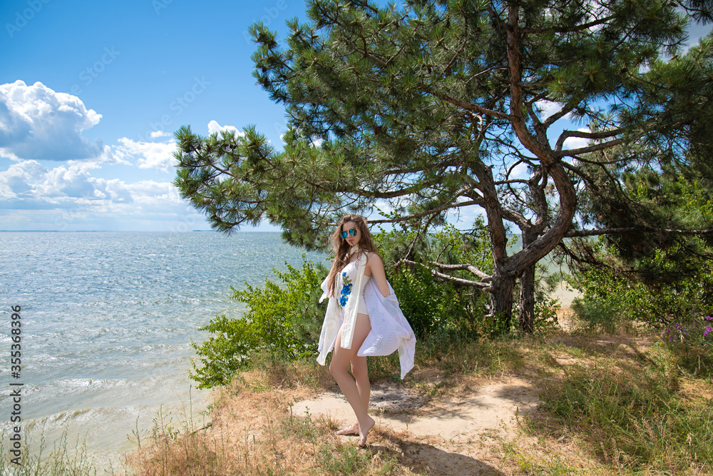 Gorgeous young woman in white swimsuit relaxing on the beach. Summer lifestyle Gorgeous young woman in white swimsuit relaxing on the beach. Summer lifestyle
