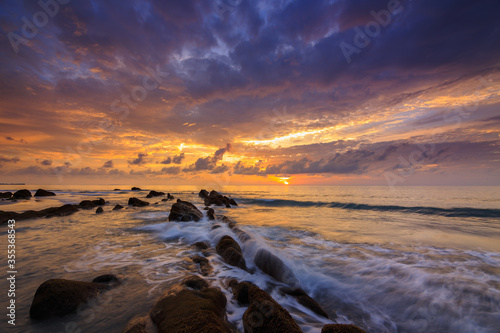 Amazing twilight Sunset seascape with sea wave hitting the green moss