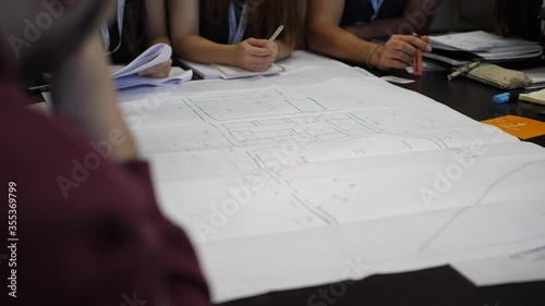 Civil engineers sitting around technical layout drawing at construction site photo