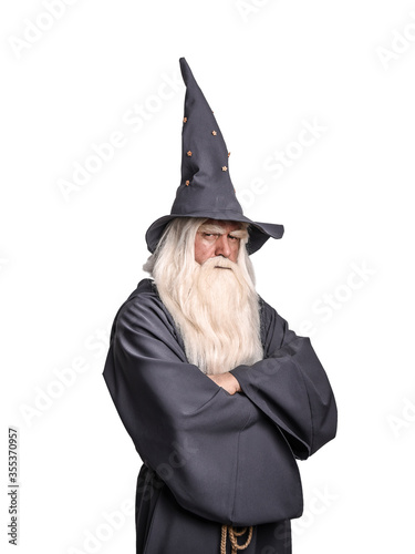 A stern grey-haired bearded wizard in a gray cassock and a cap is practicing sorcery, doing magic against a white insulating background.