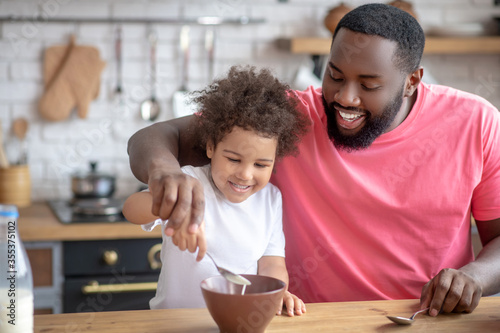 Photos African american bearded man stirring milk in his daughters plate
