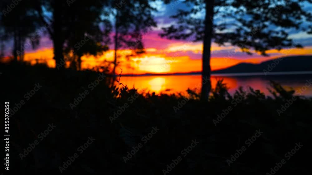 Epic, beautiful sunset at lake with trees and bushes in the foreground. Nice reflection on the water, soft bokeh, slowmotion and mountains. Epic, beautiful sunset at lake with trees and bushes in the foreground. Nice reflection on the water, soft bokeh, slowmotion and mountains.